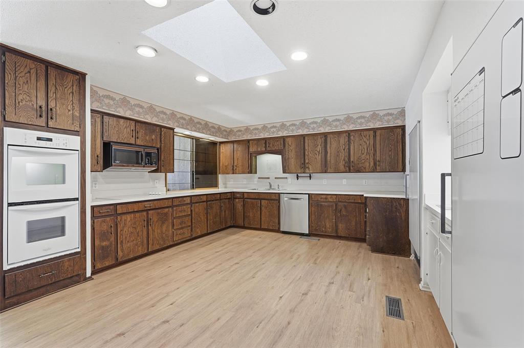 112 Virginia Lane Arlington, TX 76010 - Photo 12 of 39 a large white kitchen with a refrigerator a sink dishwasher a oven with wooden cabinets and floors