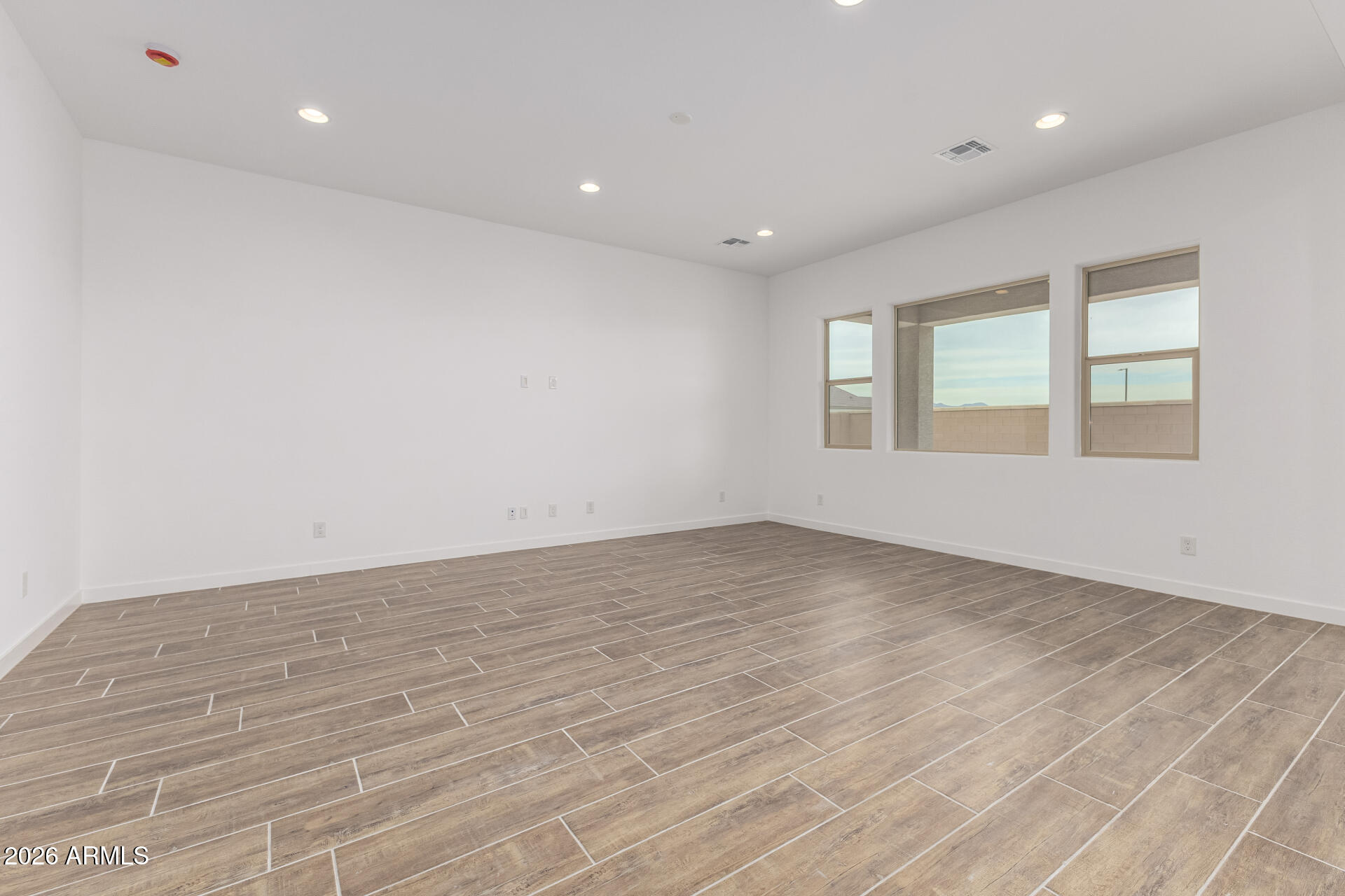 18146 West Watkins Street Goodyear, AZ 85338 - Photo 10 of 36 an empty room with wooden floor and windows
