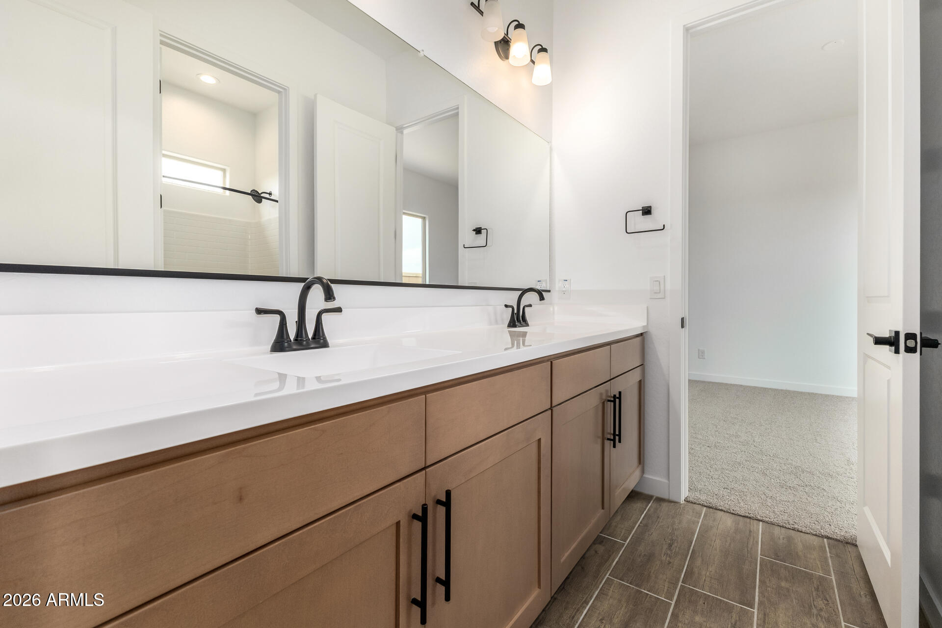 18146 West Watkins Street Goodyear, AZ 85338 - Photo 21 of 36 a bathroom with a double vanity sink a mirror and a bathtub