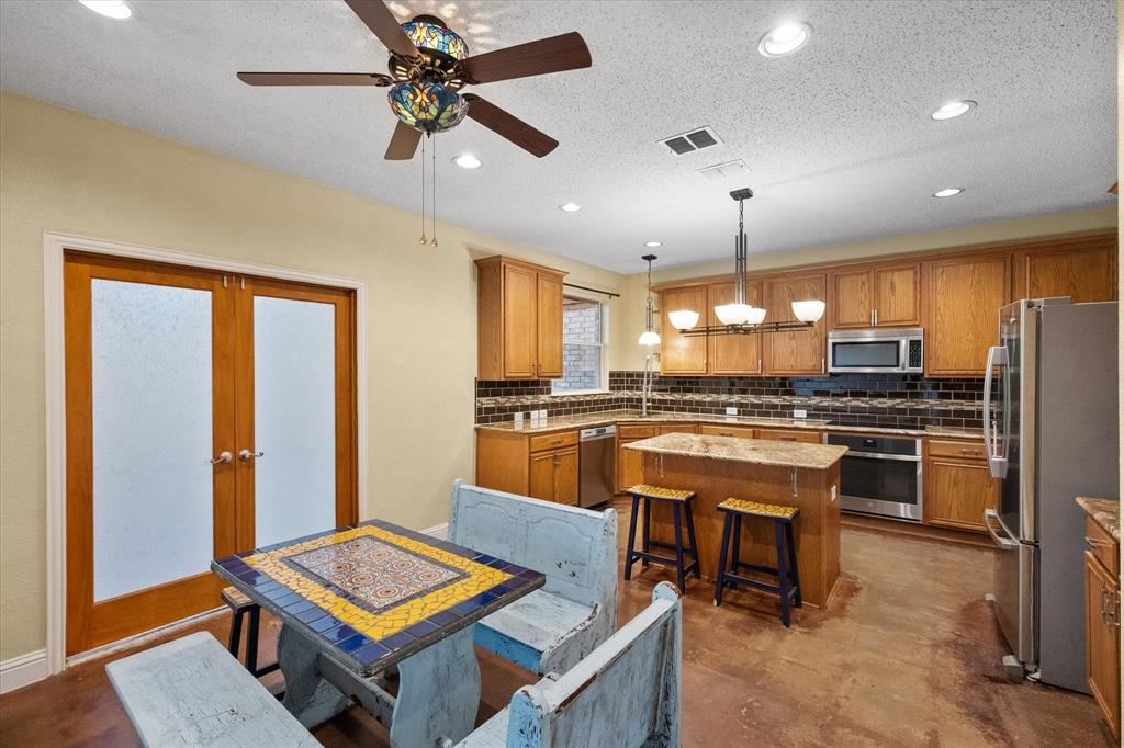 1305 Liverpool Lane Mansfield, TX 76063 - Photo 21 of 40 This kitchen and dining area features wood cabinetry, stainless steel appliances, and a central island with a granite countertop