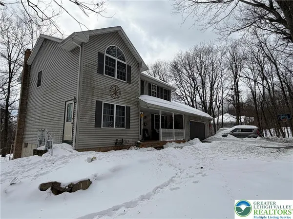 a front view of a house with a yard covered in snow