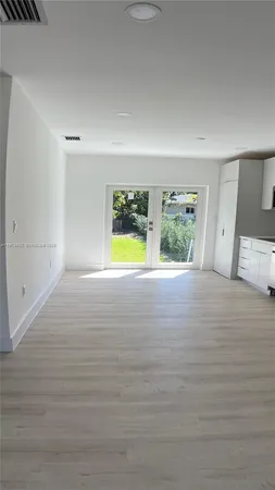 a view of an empty room with a window and wooden floor