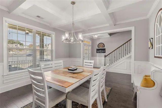 a kitchen with kitchen island a dining table chairs sink and white cabinets