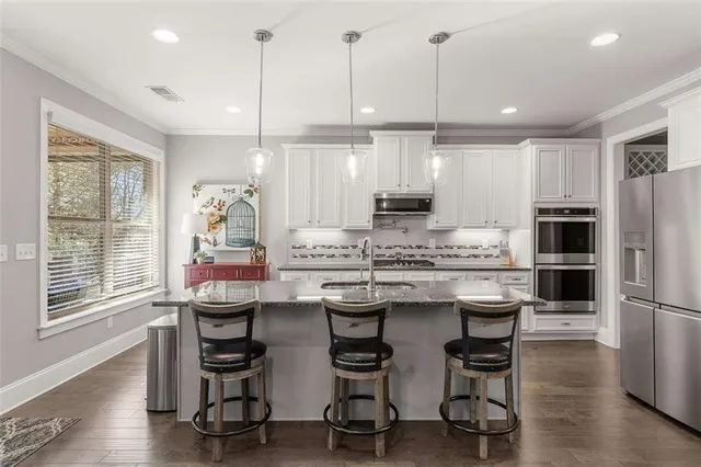 a large kitchen with kitchen island granite countertop a sink a stove refrigerator and cabinets