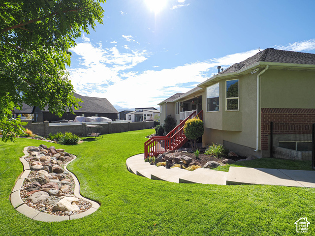 11779 South Stone Ridge Court Ridge West Riverton, UT 84065 - Photo 74 of 85 Expansive green lawn with a decorative rock feature, concrete walkway, and red-painted exterior stairs
