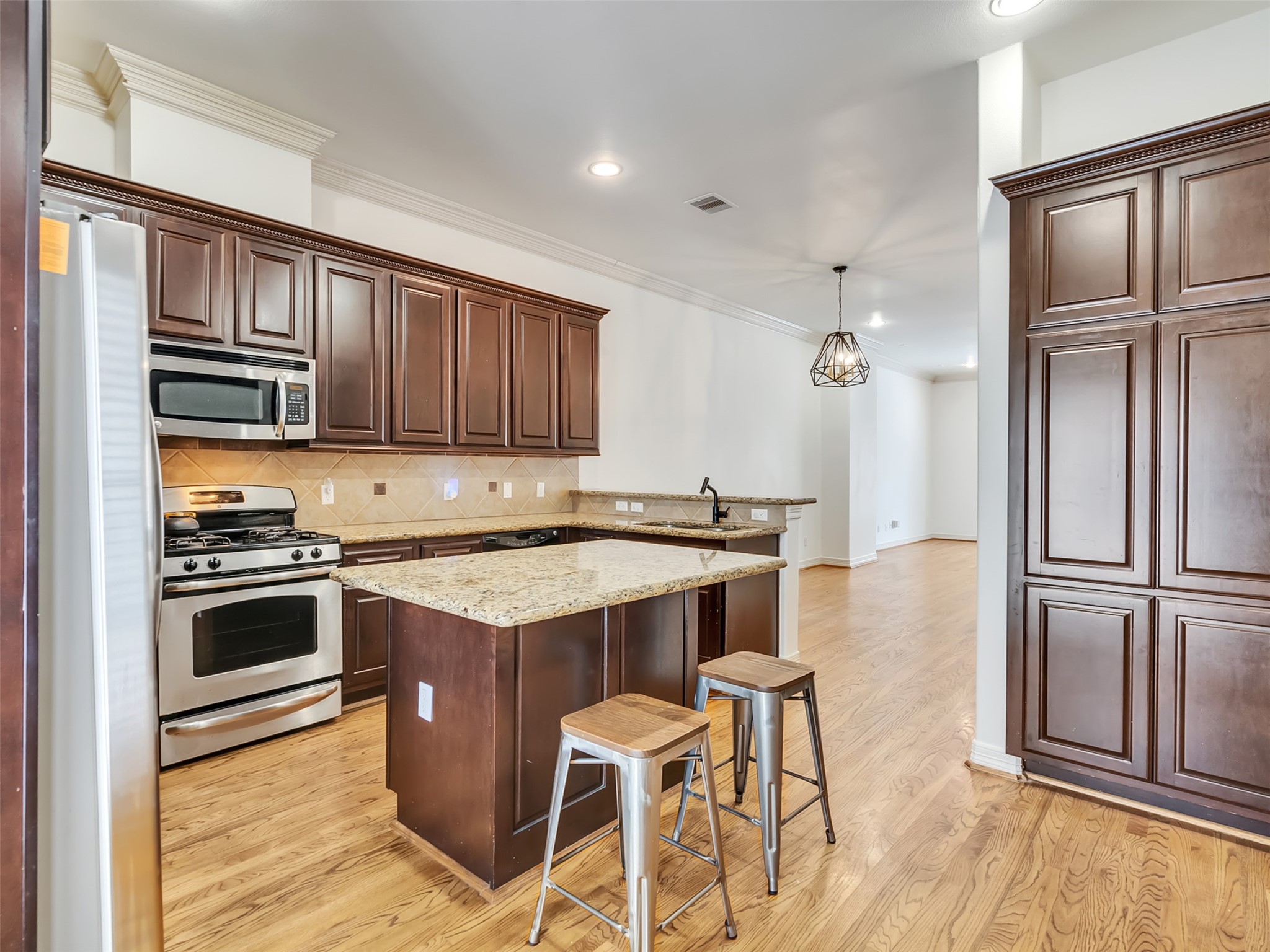 2540 Prospect Street, Unit B Houston, TX 77004 - Photo 10 of 37 a kitchen with kitchen island granite countertop wooden cabinets and stainless steel appliances