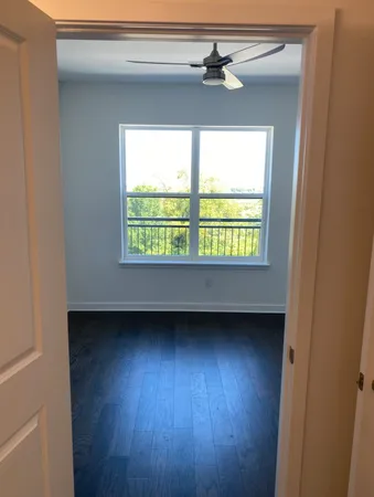 a view of an empty room with a window and wooden floor