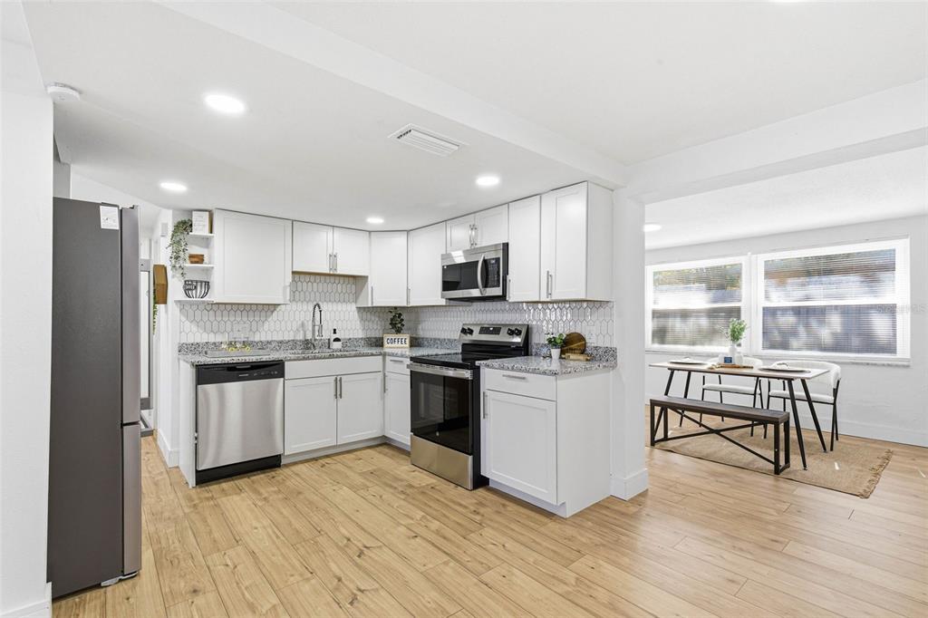 6338 Nashua Drive Port Richey, FL 34668 - Photo 14 of 49 a kitchen with a refrigerator a stove top oven a sink dishwasher a dining table and chairs with wooden floor