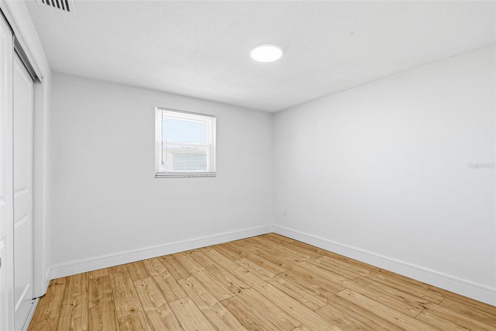 6338 Nashua Drive Port Richey, FL 34668 - Photo 33 of 49 an empty room with wooden floor and windows