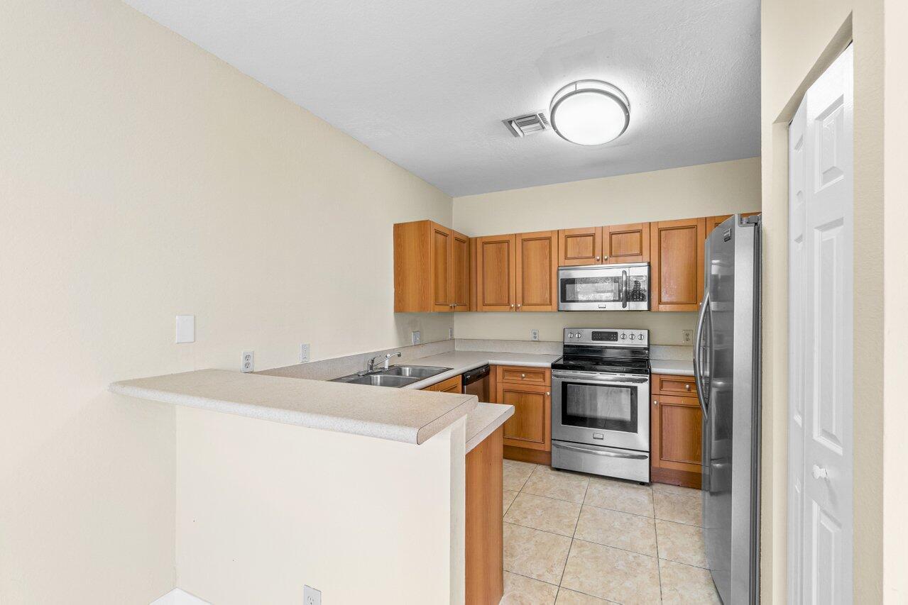809 Talia Circle, Unit 809 TALIA CIRCLE Palm Springs, FL 33461 - Photo 11 of 23 a kitchen with stainless steel appliances granite countertop a sink stove and refrigerator