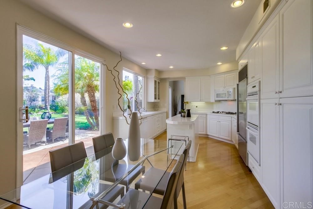 2727 Carriagedale Row La Jolla, CA 92037 - Photo 8 of 25 a kitchen with stainless steel appliances granite countertop sink refrigerator dining table and chairs