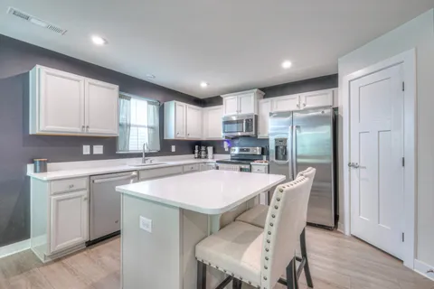 a kitchen with stainless steel appliances granite countertop a refrigerator a sink a stove a dining table and chairs