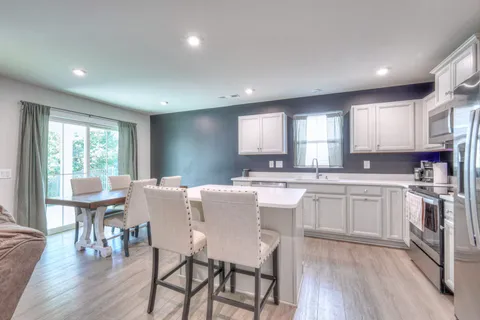 a kitchen with stainless steel appliances granite countertop a stove a sink a dining table and chairs