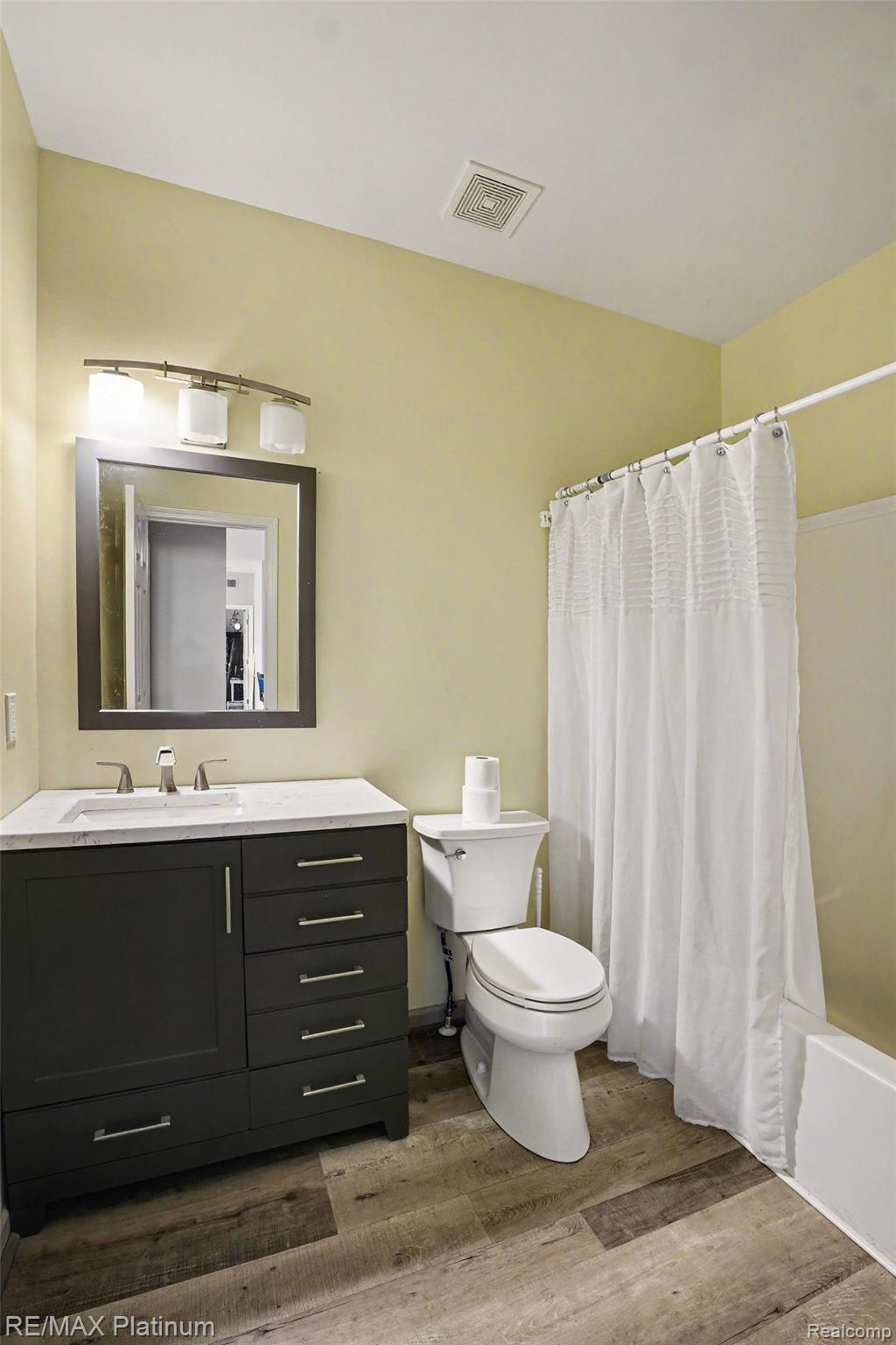 10217 Crossview Trail Howell, MI 48855 - Photo 20 of 26 Bathroom featuring a dark wood-finish vanity with a light countertop, a rectangular sink with a chrome faucet, and wood-look flooring