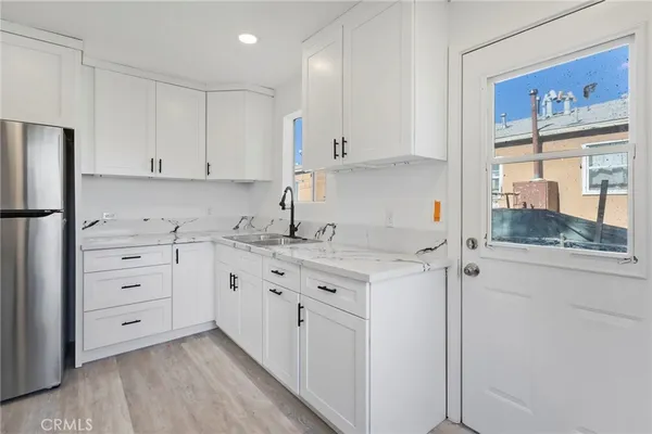 a kitchen with granite countertop white cabinets and refrigerator