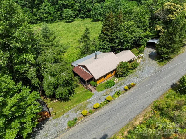 a backyard of a house with table and chairs under an umbrella