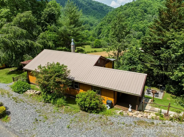 an aerial view of a house with swimming pool and large trees