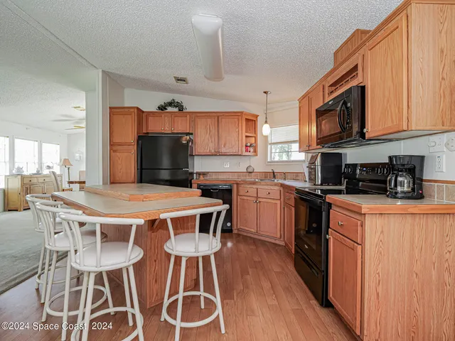 a kitchen with stainless steel appliances granite countertop a kitchen island hardwood floor sink stove dining table and chairs