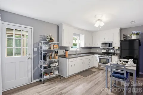 a kitchen with a stove a sink dishwasher a refrigerator and a dining table with wooden floor