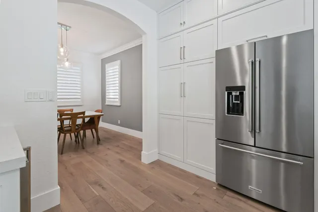 a large kitchen with a large counter top a sink stainless steel appliances and living room view