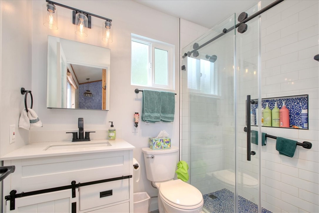 910 Sheffield Street Cambria, CA 93428 - Photo 18 of 29 a bathroom with a sink a toilet a mirror a vanity and shower