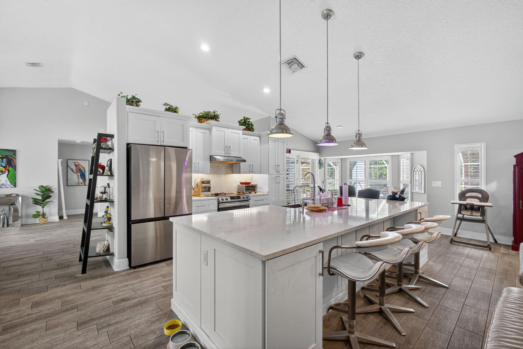 13033 160th Road North Jupiter, FL 33478 - Photo 15 of 79 a kitchen with stainless steel appliances granite countertop a refrigerator a sink dishwasher a stove and a dining table with wooden floor