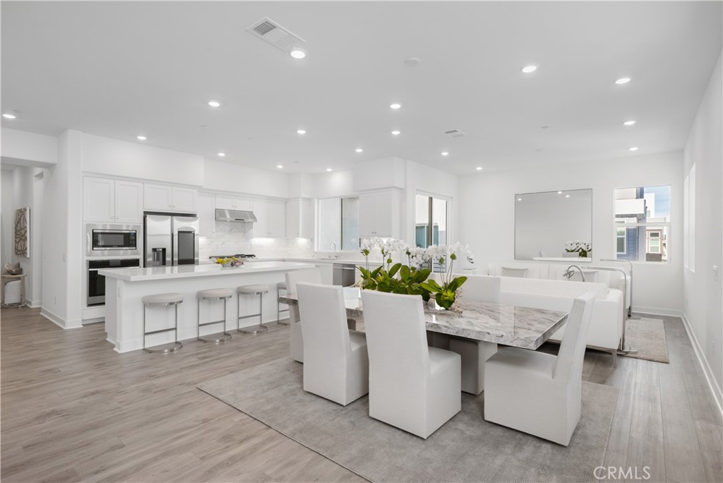 27225 Cranmore Way, Unit 101 Valencia, CA 91381 - Photo 1 of 36 a living room with stainless steel appliances kitchen island granite countertop lots of white furniture a dining table and chairs