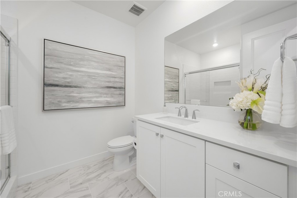 27225 Cranmore Way, Unit 101 Valencia, CA 91381 - Photo 12 of 36 a bathroom with a granite countertop sink a toilet and a mirror