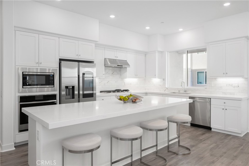 27225 Cranmore Way, Unit 101 Valencia, CA 91381 - Photo 2 of 36 a large kitchen with granite countertop a counter space chairs stainless steel appliances and cabinets