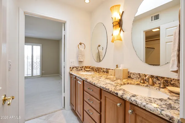 a bathroom with a granite countertop double vanity sink and a mirror