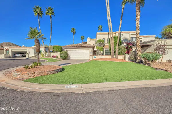 a view of a house with a yard and a car park in the background