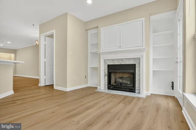 a view of an empty room with wooden floor fireplace and a window