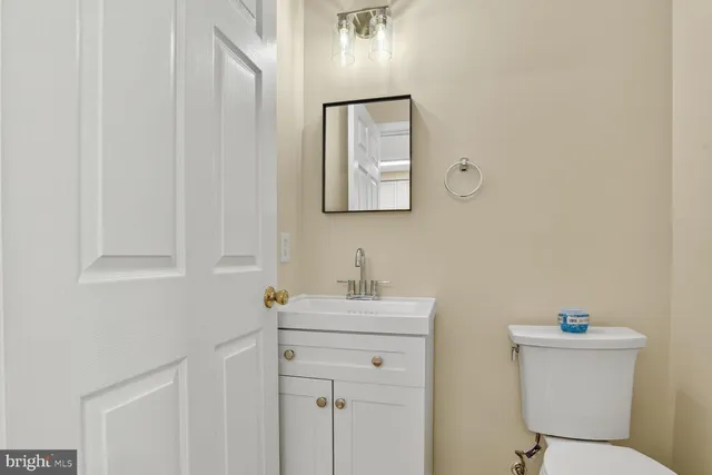 a bathroom with a toilet sink vanity and mirror
