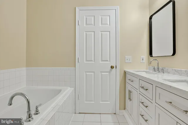 a bathroom with a granite countertop sink a mirror and a bathtub