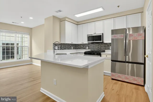 a kitchen with a refrigerator a stove a sink and a oven with wooden floor