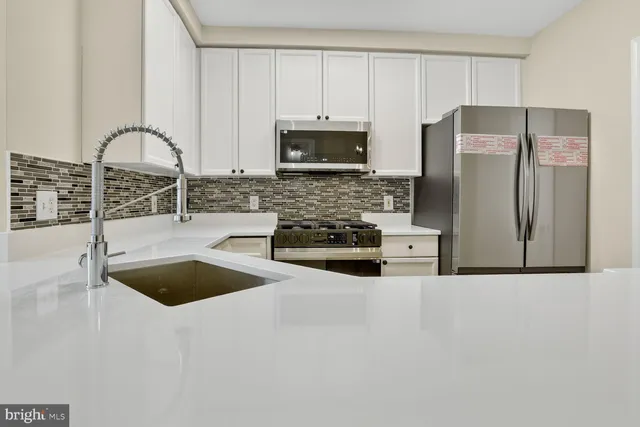 a kitchen with granite countertop a sink a stove and refrigerator