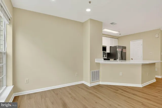 a view of kitchen with stainless steel appliances wooden floor and cabinets