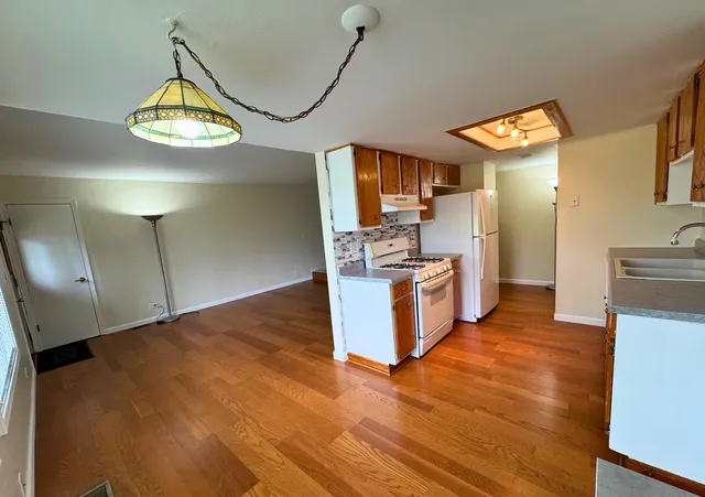 a kitchen with stainless steel appliances granite countertop a stove a refrigerator a sink dishwasher and white cabinets with wooden floor