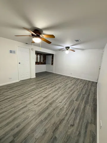 a view of an empty room with wooden floor fireplace and a window
