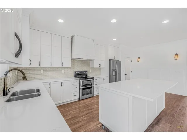 a kitchen with stainless steel appliances a refrigerator sink and white cabinets