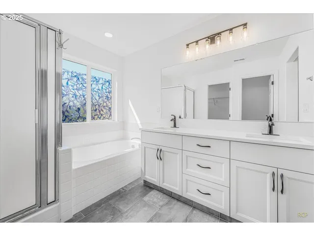 a bathroom with a double vanity sink a mirror and a bathtub