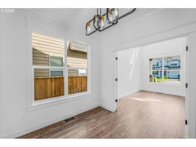 a view of an empty room with window and wooden floor