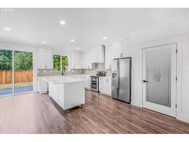 a kitchen with stainless steel appliances granite countertop a refrigerator a sink dishwasher and a oven with wooden floor