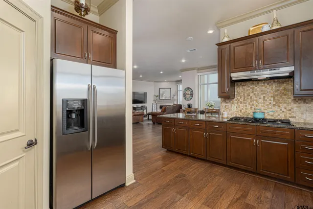 a kitchen with stainless steel appliances granite countertop a refrigerator a sink a stove and oven with wooden floors