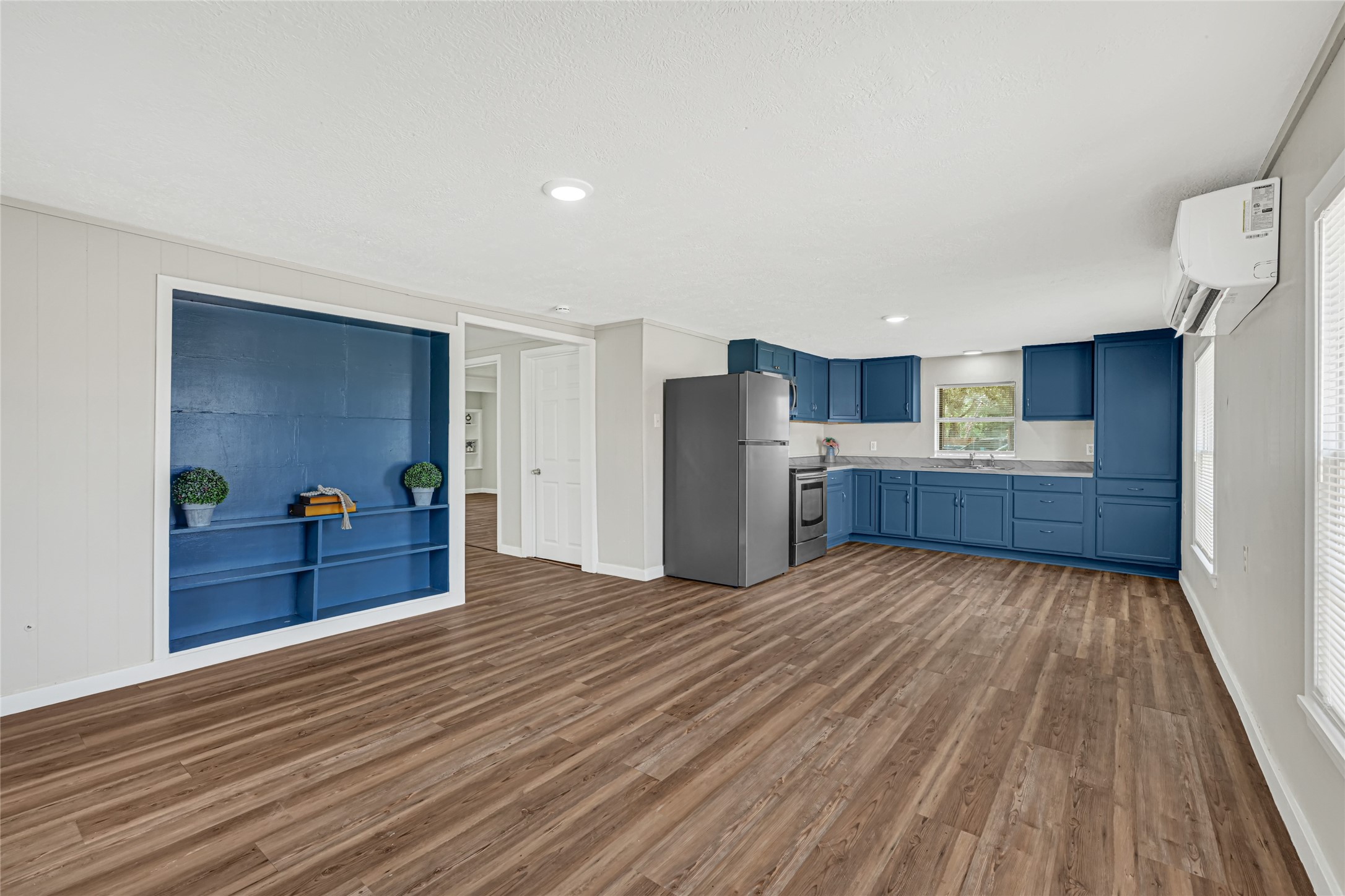 4568 Dunnam Road, Unit B Houston, TX 77345 - Photo 3 of 15 Spacious open-concept kitchen and dining area with stylish blue cabinetry, stainless-steel appliances, and wood laminate flooring.