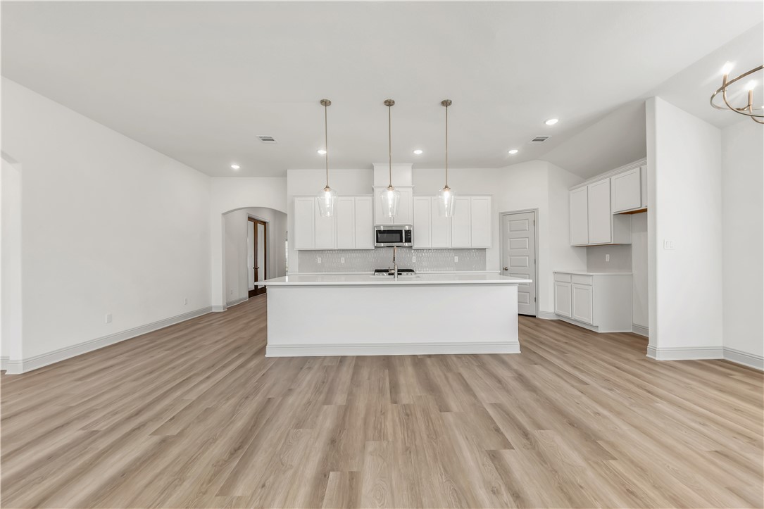 5955 Eldora Drive College Station, TX 77845 - Photo 15 of 36 a large white kitchen with kitchen island a sink wooden floor and stainless steel appliances