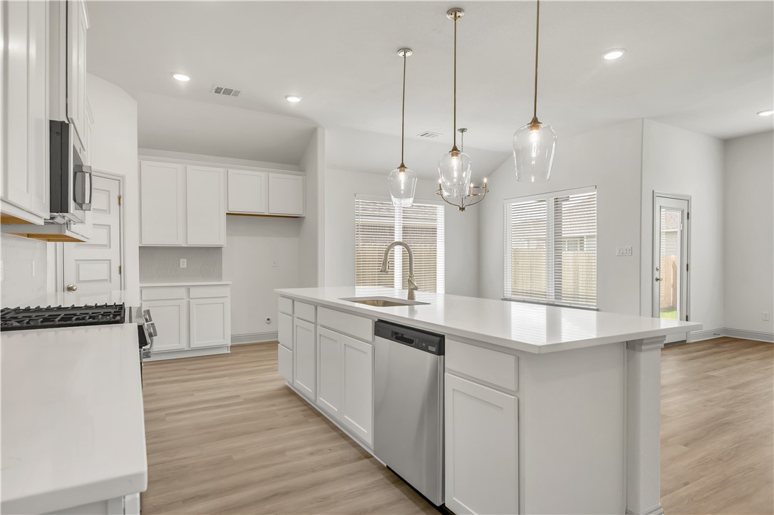 5955 Eldora Drive College Station, TX 77845 - Photo 10 of 36 Kitchen with appliances with stainless steel finishes, recessed lighting, light wood-type flooring, white cabinetry, and lofted ceiling