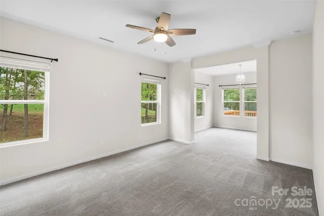 an empty room with windows and ceiling fan