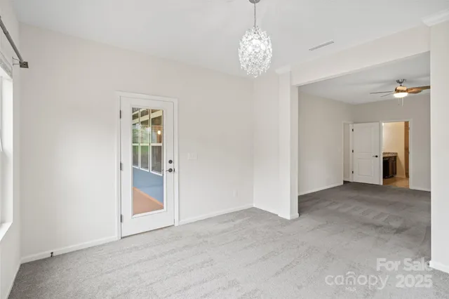 an empty room with chandelier and windows