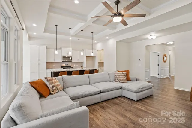 a living room with furniture kitchen view and a chandelier